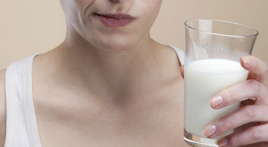 woman contemplating drinking a glass of milk